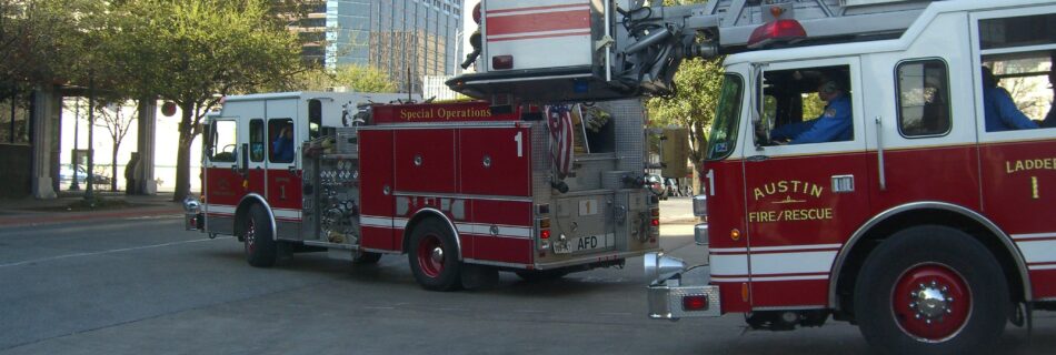 Two Austin Fire trucks pulling out of a fire station