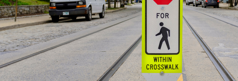 Sign that says "State Law Stop for [pedestrian] within crosswalk" on a street